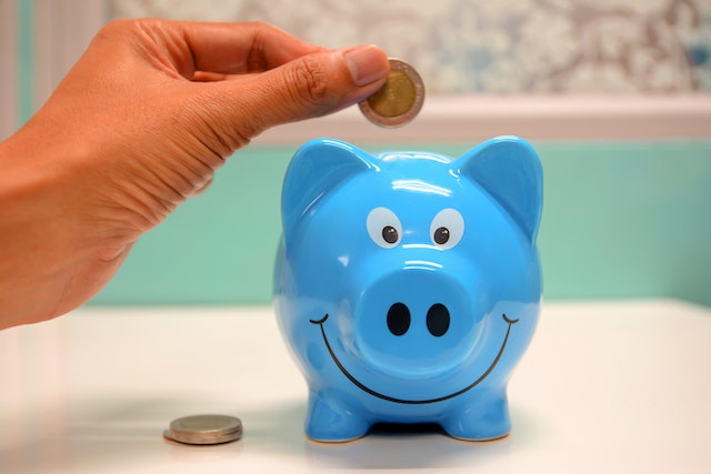 A hand putting a coin in a piggy bank as a symbol of life after bankruptcy