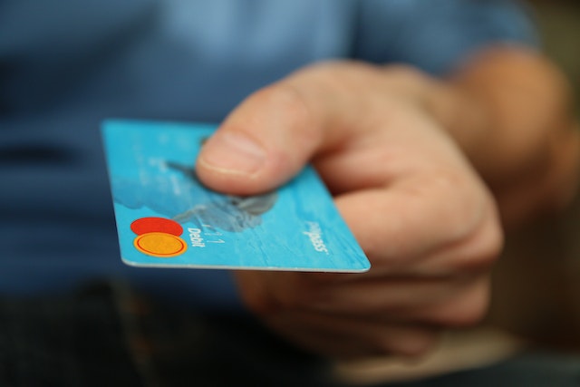 A man holds a blue credit card in his hand